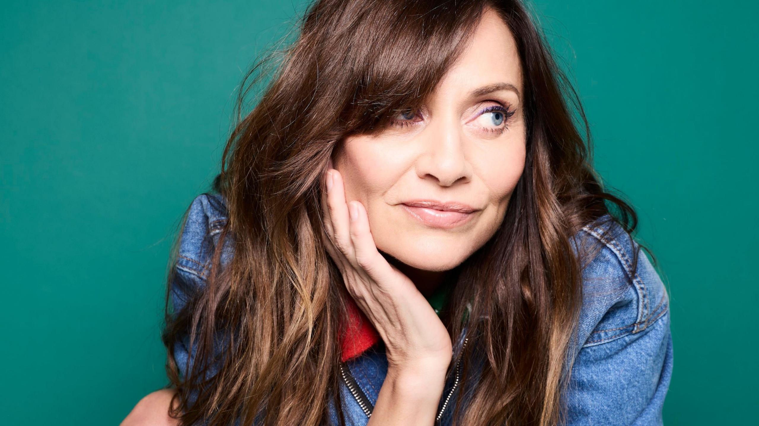 Promotional photograph of Natalie Imbruglia in a denim jacket, with her head resting in her right hand