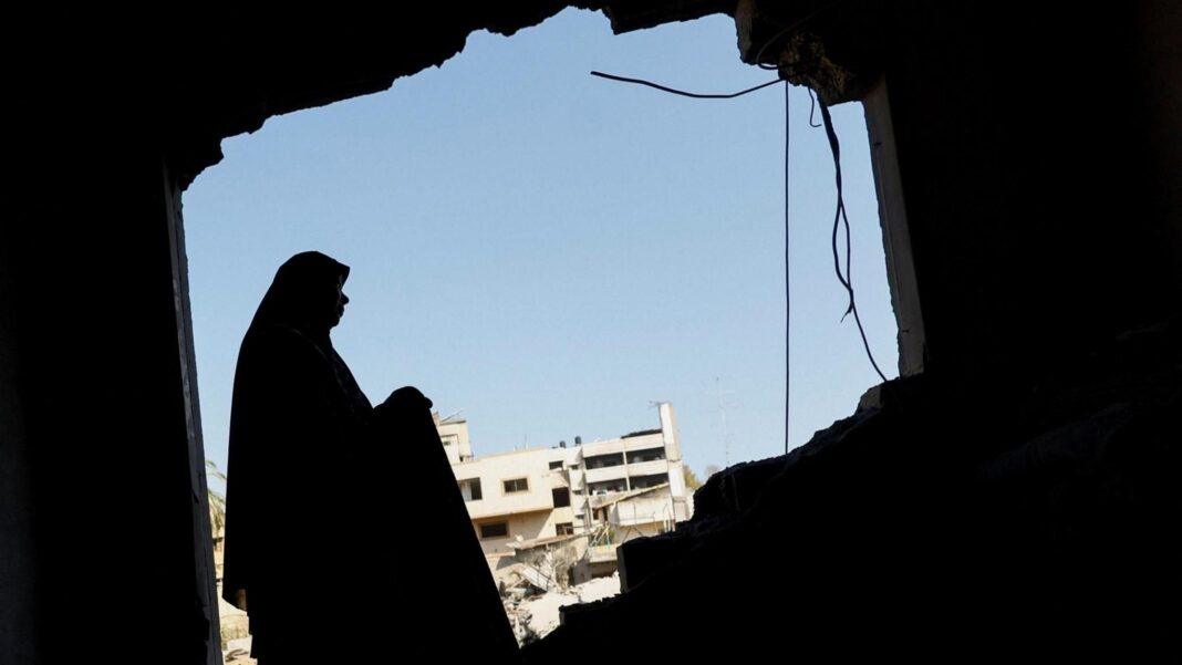 Reports of violence against women in Gaza surge, UN agency finds A file photo showing a Palestinian woman inspecting her damaged home after an Israeli strike on a nearby mosque, in Gaza City (29 July 2026)