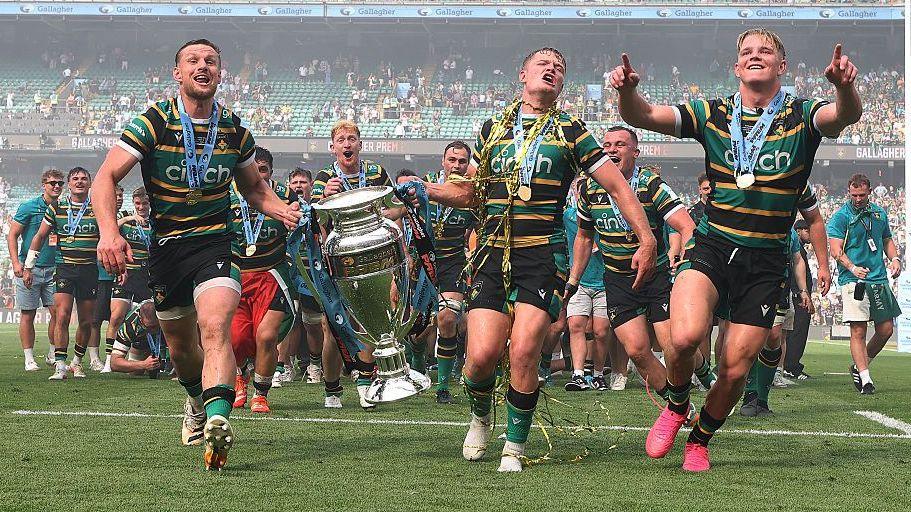 Henry Pollock celebrates June's Prem final win over Exeter with his Northampton team-mates Rory Hutchinson and Fin Smith, who are carrying the trophy as they run in the direction of the photographer's camera