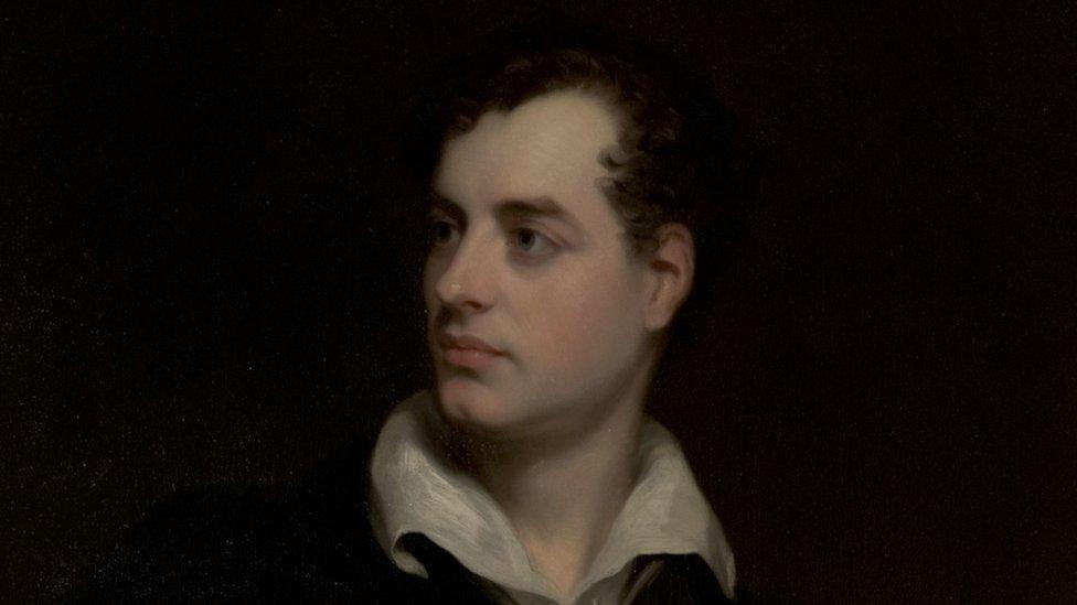 A young Byron painted in oils, he has dark hair and dark eyes and a fair skin, and is wearing a white shirt which is open at the collar.