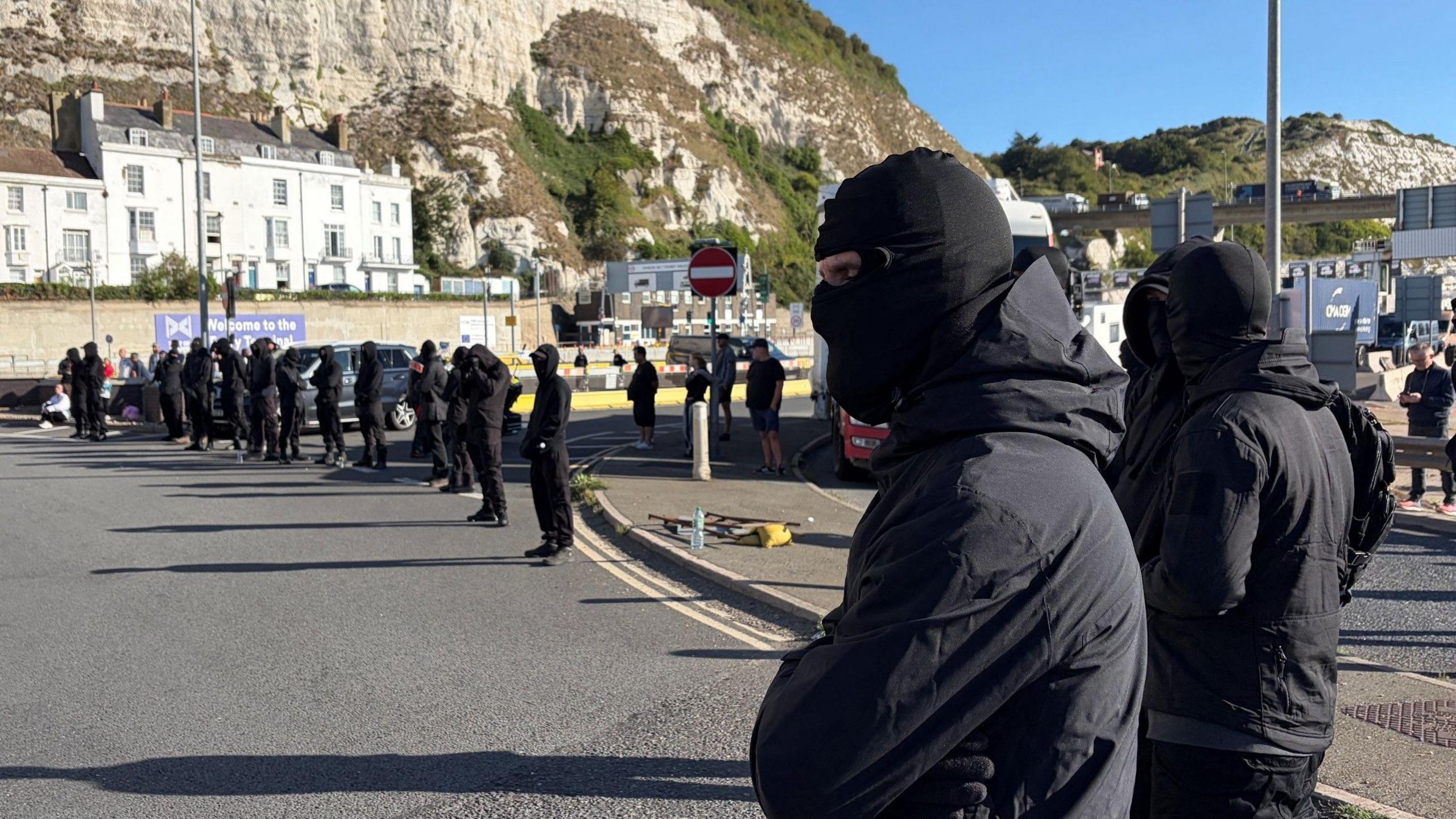 A row of masked men block a road at the entrance to the Port of Dover.