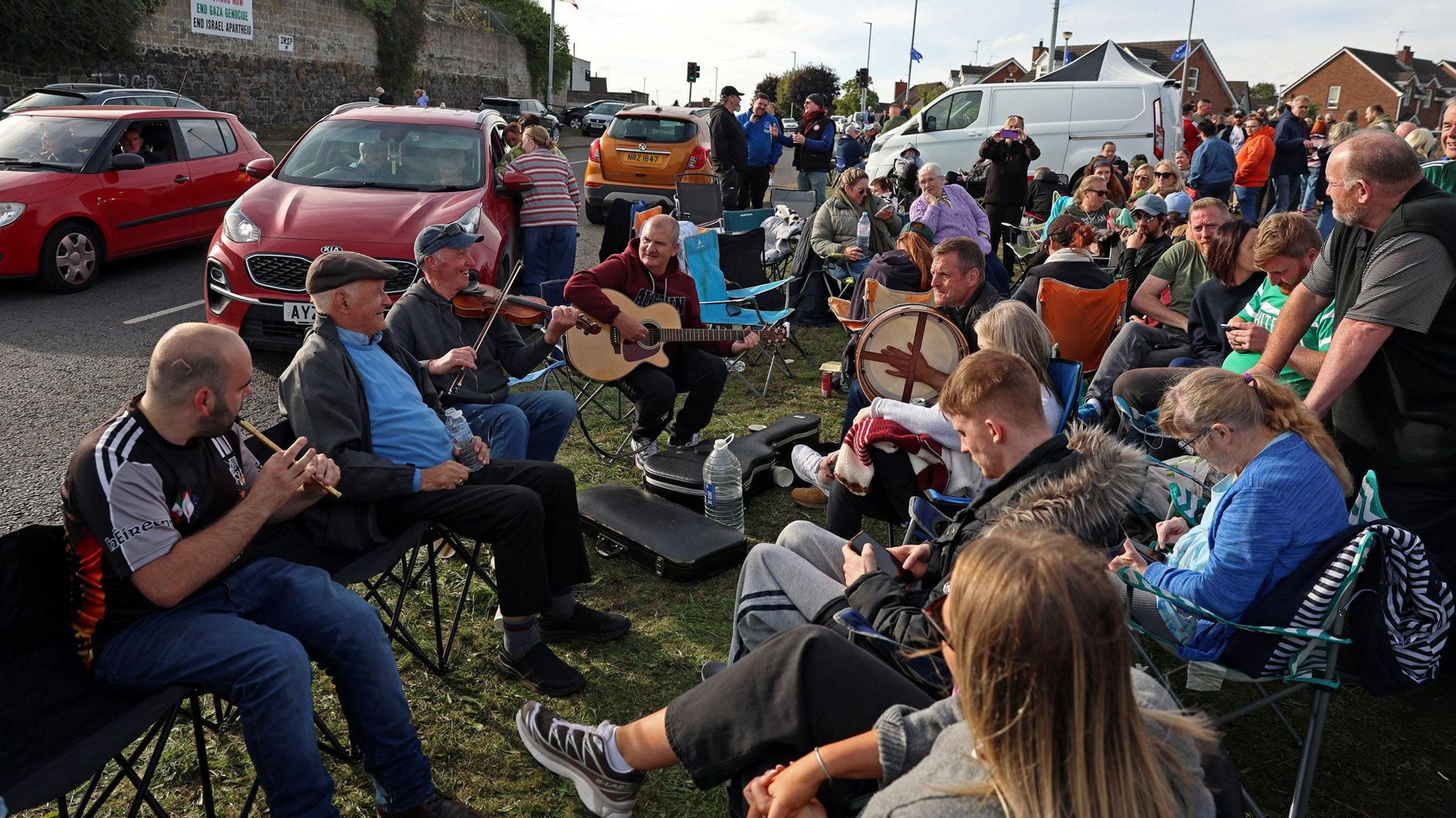 Group of people eat and play music on the side of the road