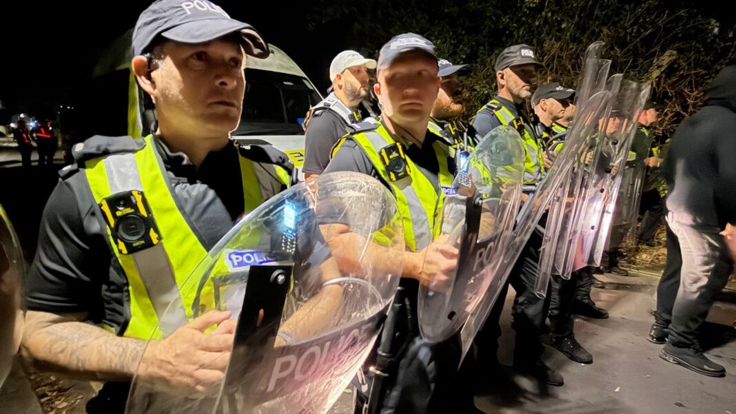Police officers stand in line in riot gear at scene of Portsmouth protest