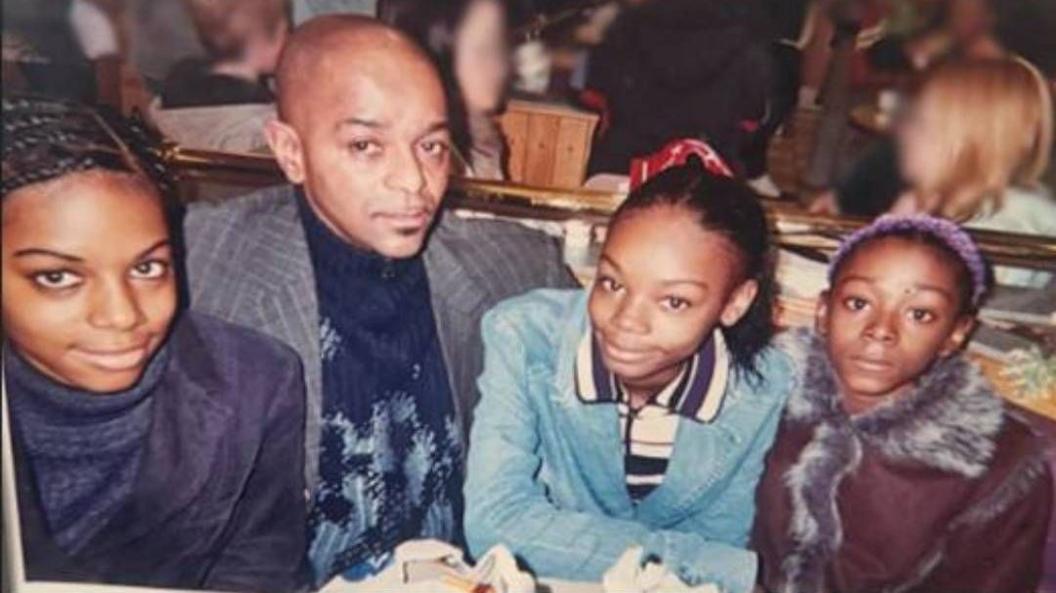 The three sisters, seen as teenagers, and their father sit together at a restaurant table, from left to right, Jane Adetoro, Joseph, Christina Walters and Rebecca Walters.