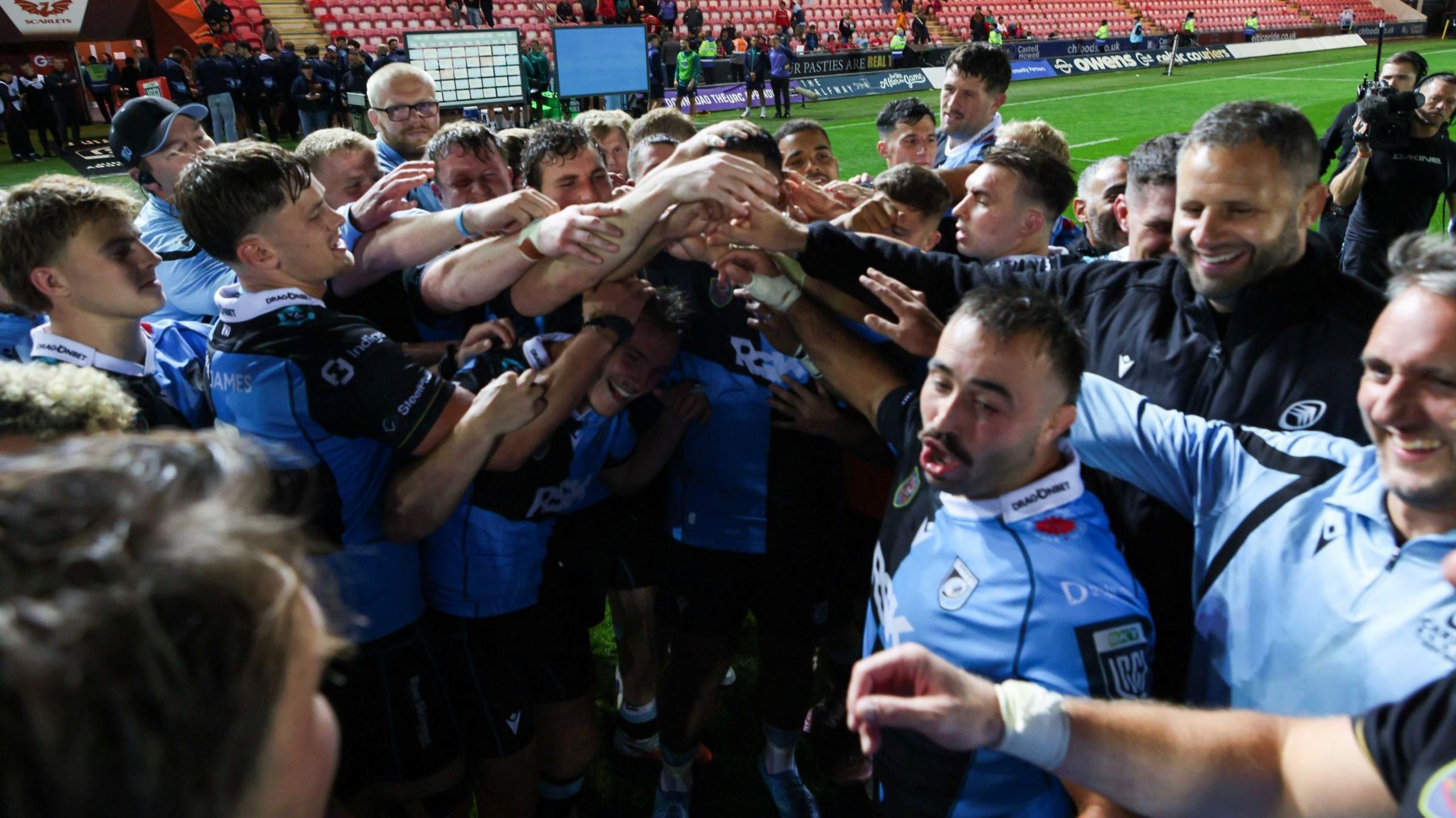 Cardiff squad in a celebration huddle after beating Scarlets