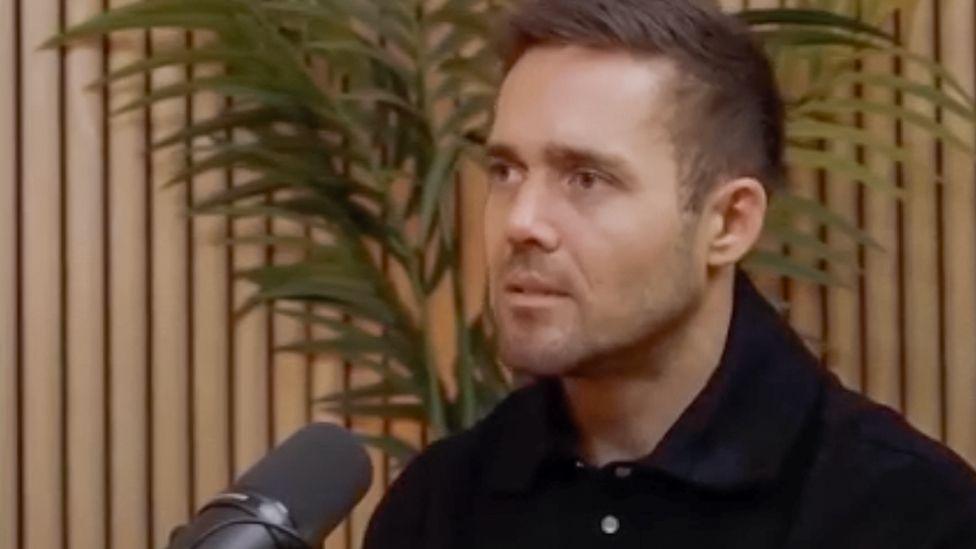Spencer Matthews sitting in front of a microphone as if speaking on a podcast.