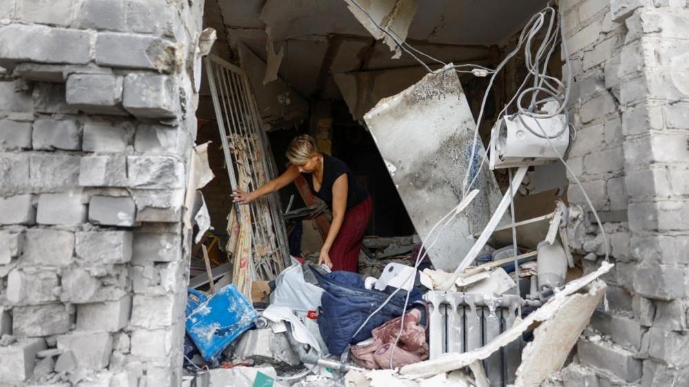 A woman in Ukraine's town of Boryspil, outside Kyiv, collects belongings from her flat destroyed by overnight Russian strikes. Photo: 1 September 2026