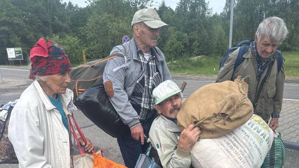 Four people carrying belongings all wearing coats