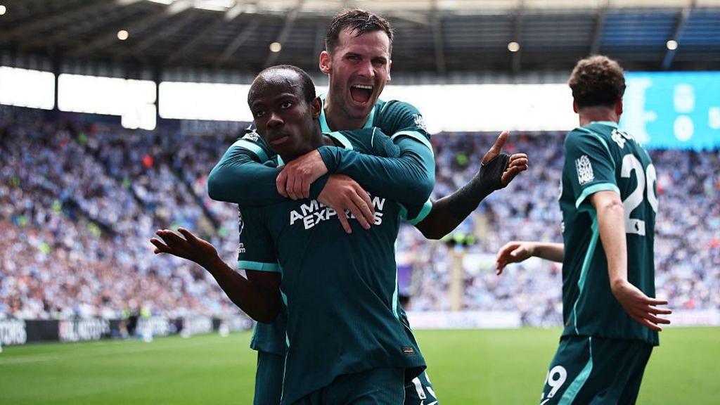 Brighton's Malick Yalcouye make a shrugging action in celebration, while being mobbed by Brighton team-mate Pascal Gross