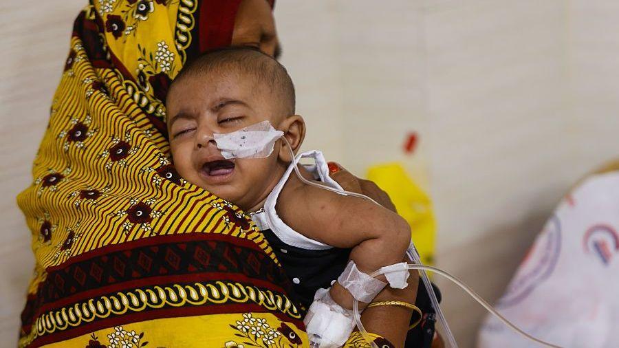 A crying baby is held by their mother