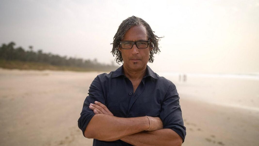 Historian David Olusoga pictured wearing a black shirt. He wears glasses and is seen with his arms crossed.