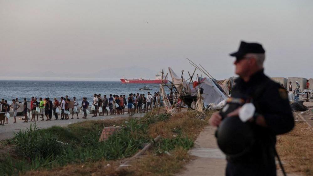 Migrants queue for a Red Cross food distribution at Trampolin beach, following recent mass crossings of migrants from Morocco to Ceuta.