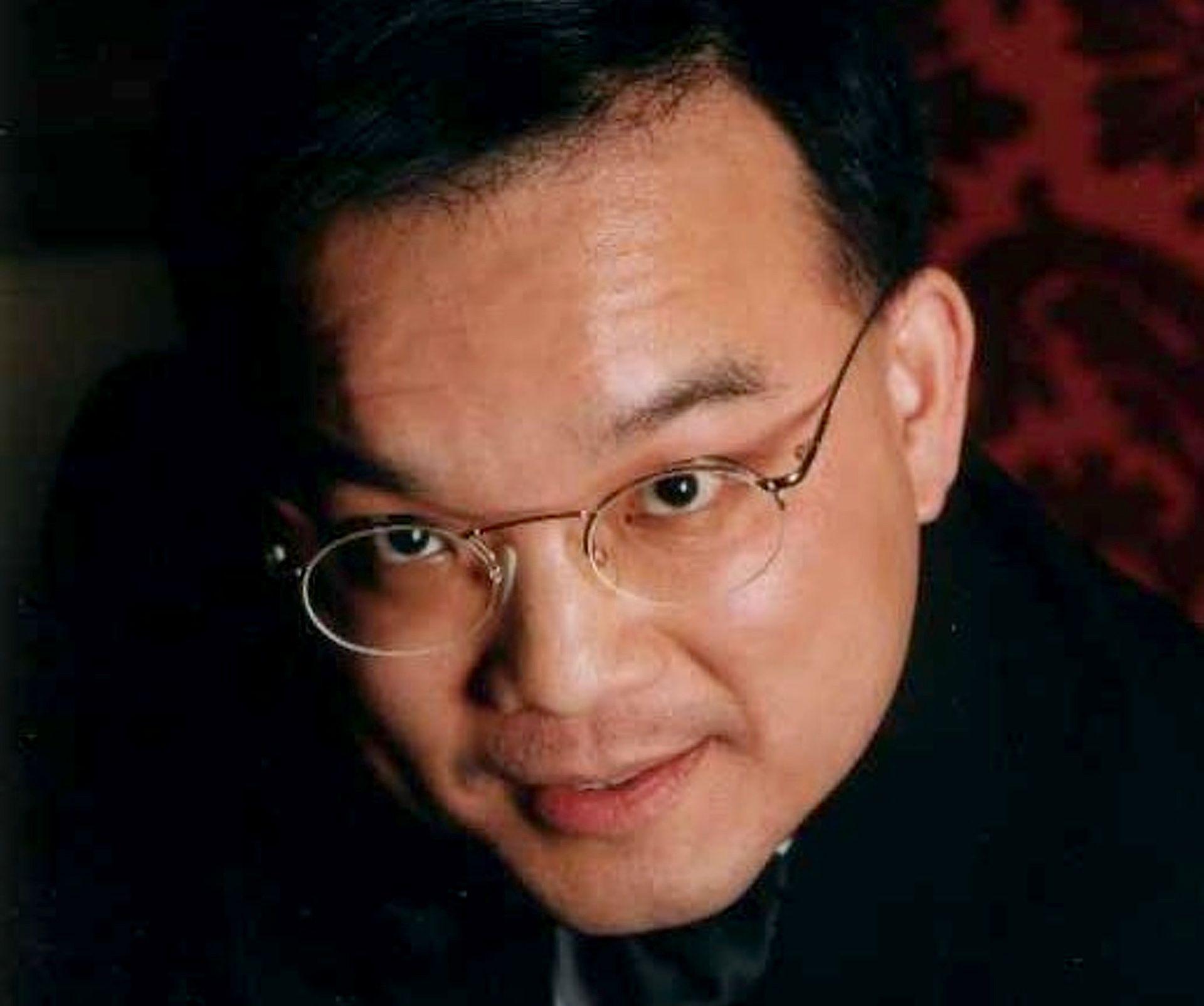 Close up image of Kenneth Law's face. He is looking at the camera and is wearing glasses.