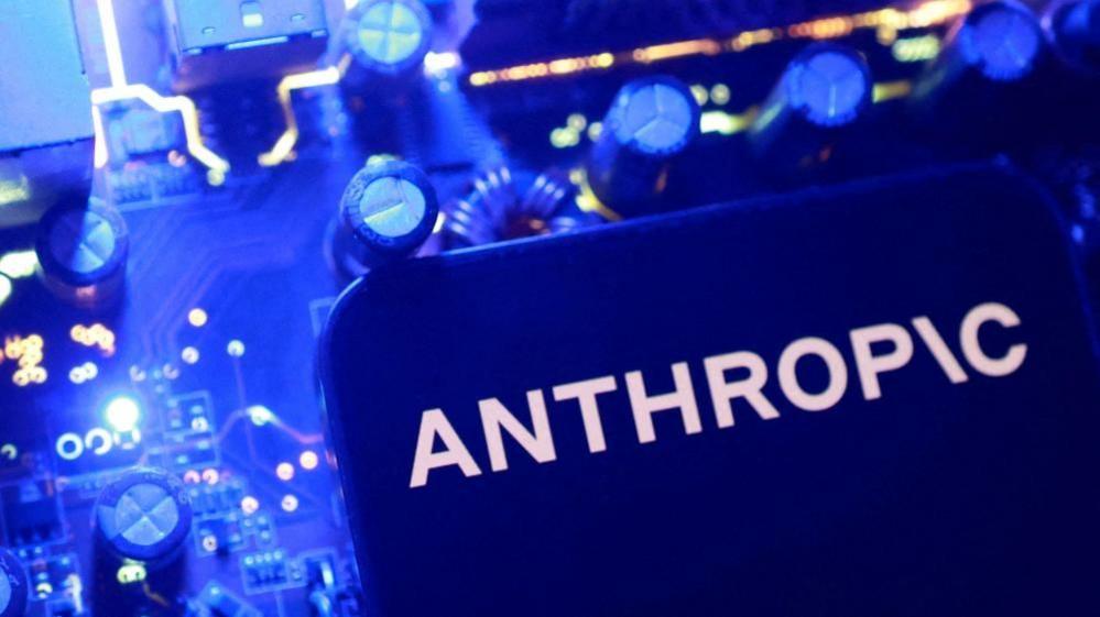 A blue  Anthropic logo on a flat surface with blue nobs and dials in the background.