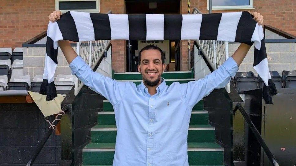 Salisbury FC owner Ali Alhamad holding a black and white scarf above his head