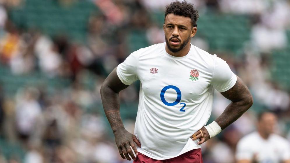 Courtney Lawes standing on the pitch with an England shirt on and his hands on his hips