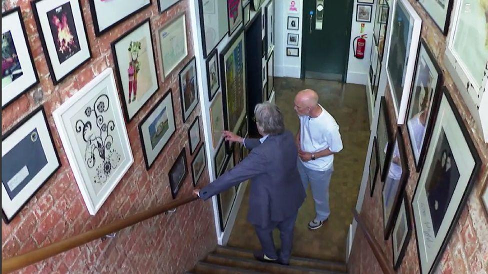 Sir Paul Smith showing BBC reporter Colin Paterson the walls of his London office, which are packed with artworks
