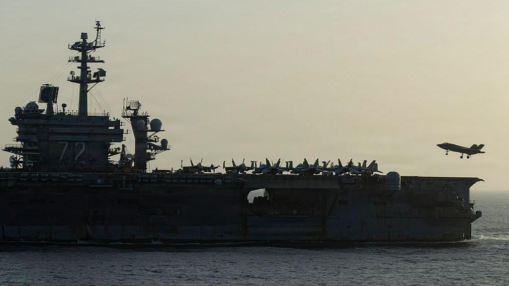 Side view of USS Abraham Lincoln as a small jet lands on it