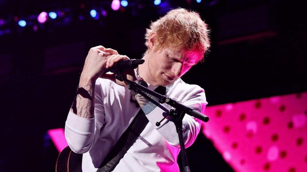 Ed Sheeran addresses Macklemore controversy at Philadelphia show Ed Sheeran looks down at stage while holding a microphone in a mic stand against a pink and black background as he performs onstage in New York in December.
