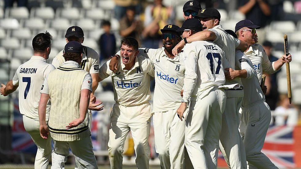 Warwickshire fast bowler Ethan Bamber celebrates in the middle of a huddle of Bears players after taking the last wicket against Leicestershire at Edgbaston to win the county title (26 September 2026)