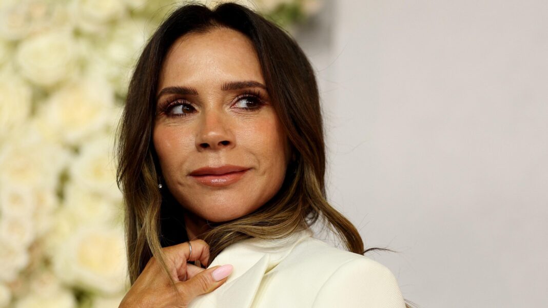 How Victoria Beckham turned her fashion firm around and made it profitable Victoria Beckham head and shoulders, looking to one side with a hand on the collar of a cream jacket, in front of a display of cream roses