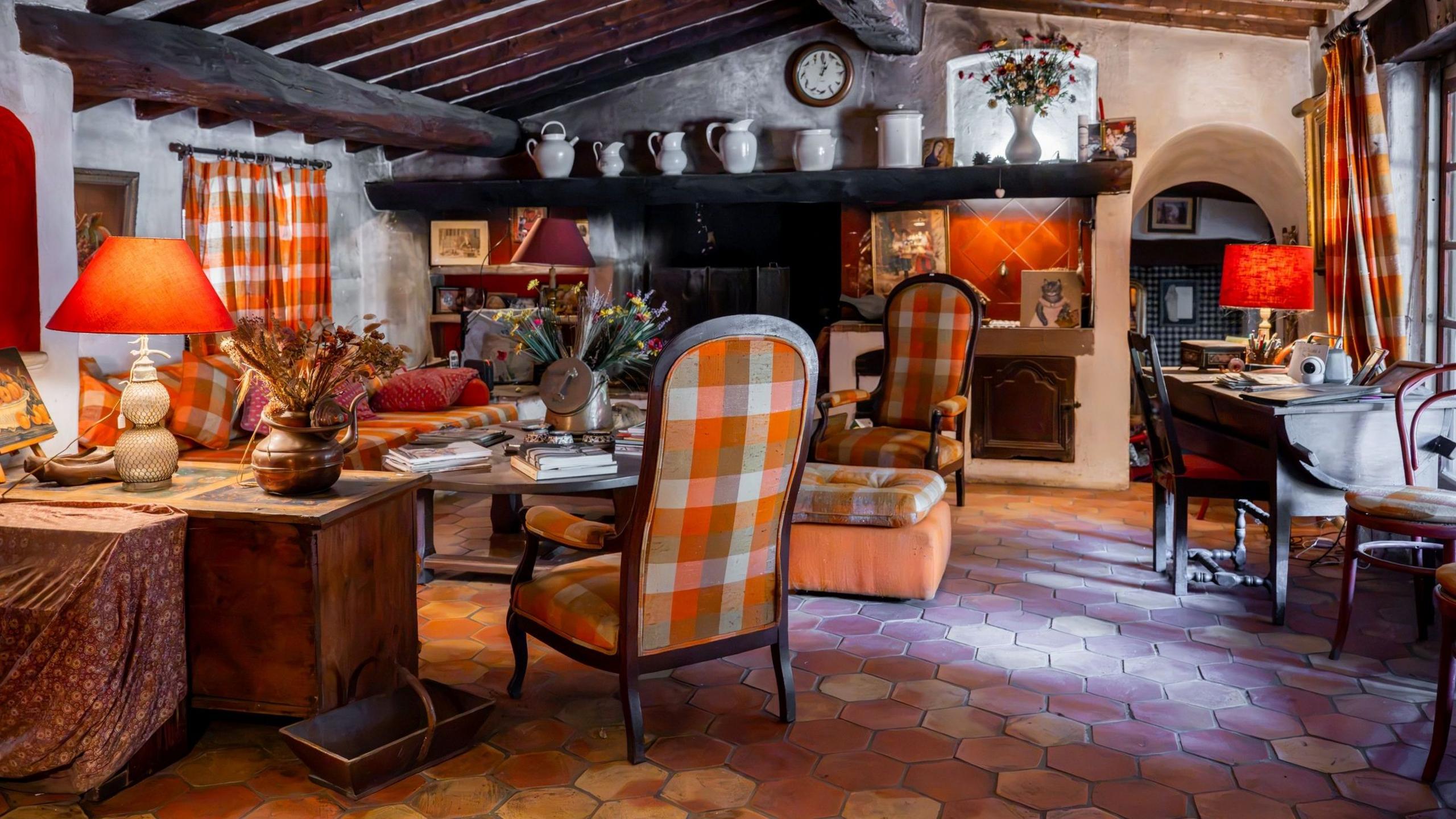 Bardot's St Tropez home, what appears to be a traditional French country house,  has beamed ceilings, curtains and large chairs covered in the same orange check material, and a terracotta tiled floor