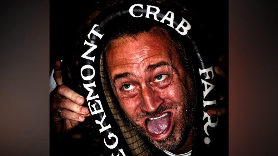 World Gurning Championship winners crowned Will Mellor distorting his face with his mouth wide open and his tongue pushing against his lower lip. He is holding a large black horse collar which is around his head, on which is written in white letters Egremont Crab Fair.