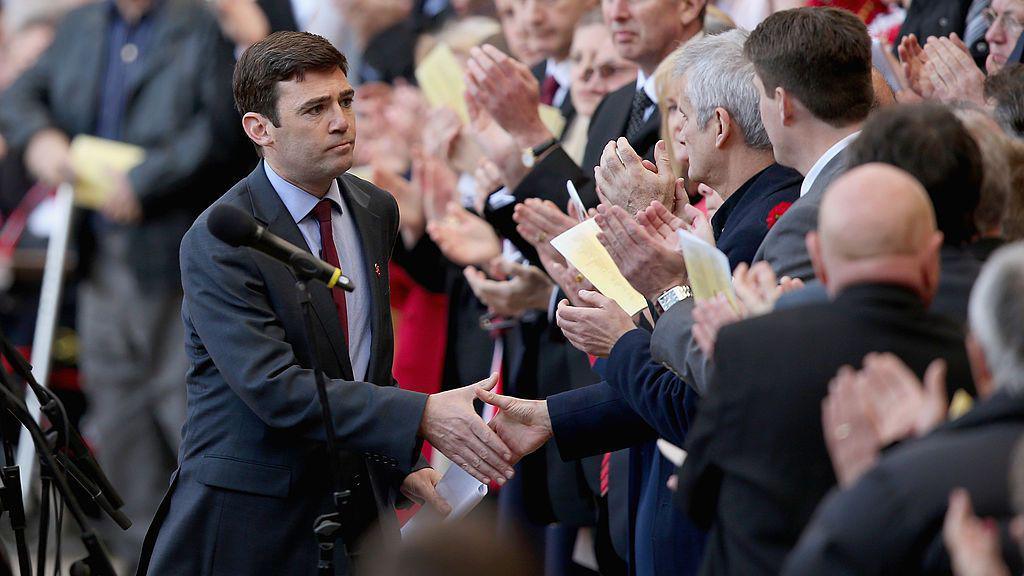 Andy Burnham shakes hands with a member of the crowd, applauding after his speech at Anfield Stadium in 2014.