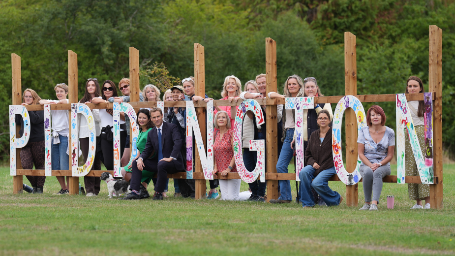 Shadow home secretary Chris Philp (centre) and shadow minister for women and equalities Joy Morrissey (centre left) sit on a hand-made 'Piddington' sign with residents of Piddington in Oxfordshire