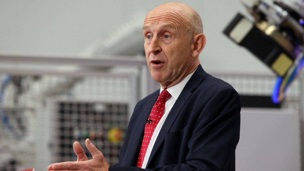 Chancellor John Healey wearing a dark suit, white shirt and red tie delivering a speech
