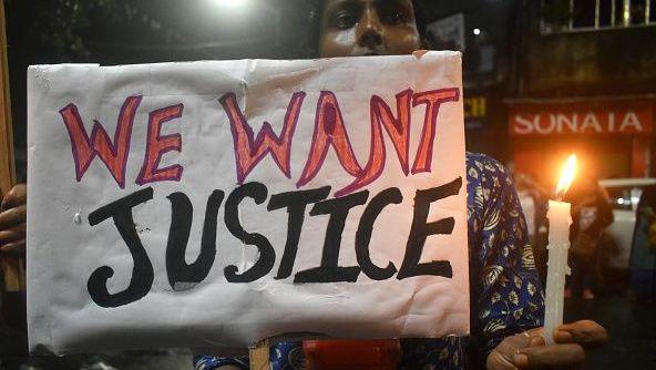A woman is holding a placard and candle while protesting over the sexual assault in Kolkata, India, on August 18, 2024.