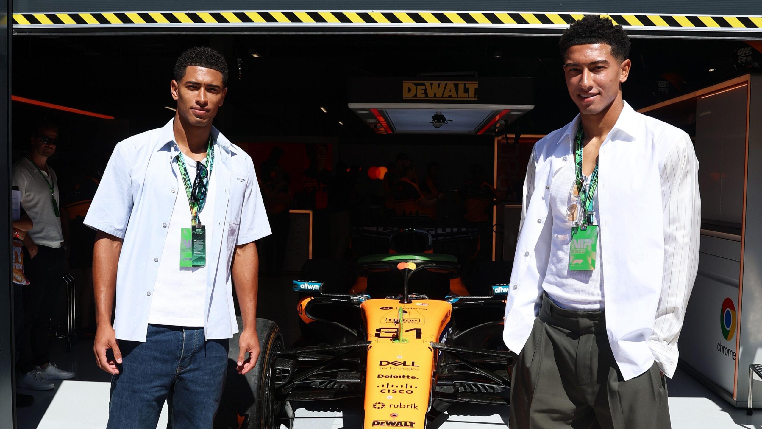 Jude Bellingham and Jobe Bellingham pose next to Oscar Piastri's McLaren in the garage before the Spanish Grand Prix