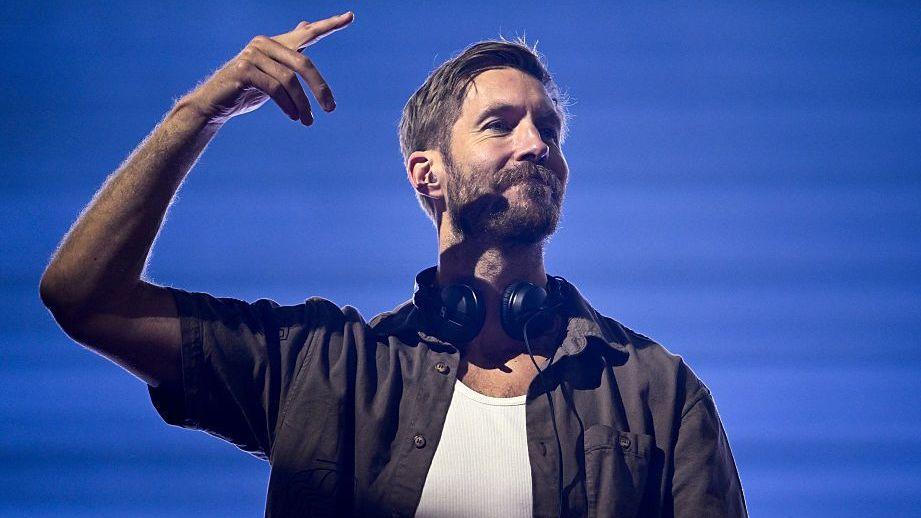 DJ Calvin Harris with headphones round his neck in a dark shirt with a white vest top underneath
