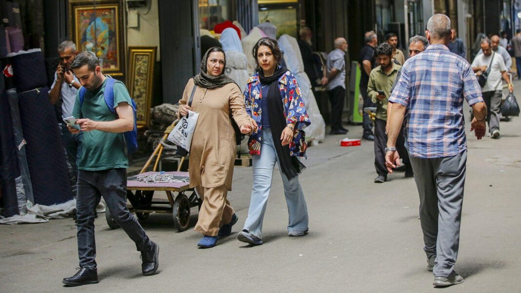 How could US-Iran conflict end? Three experts give their views Several people walk on the streets of Tehran on a shaded street in July.