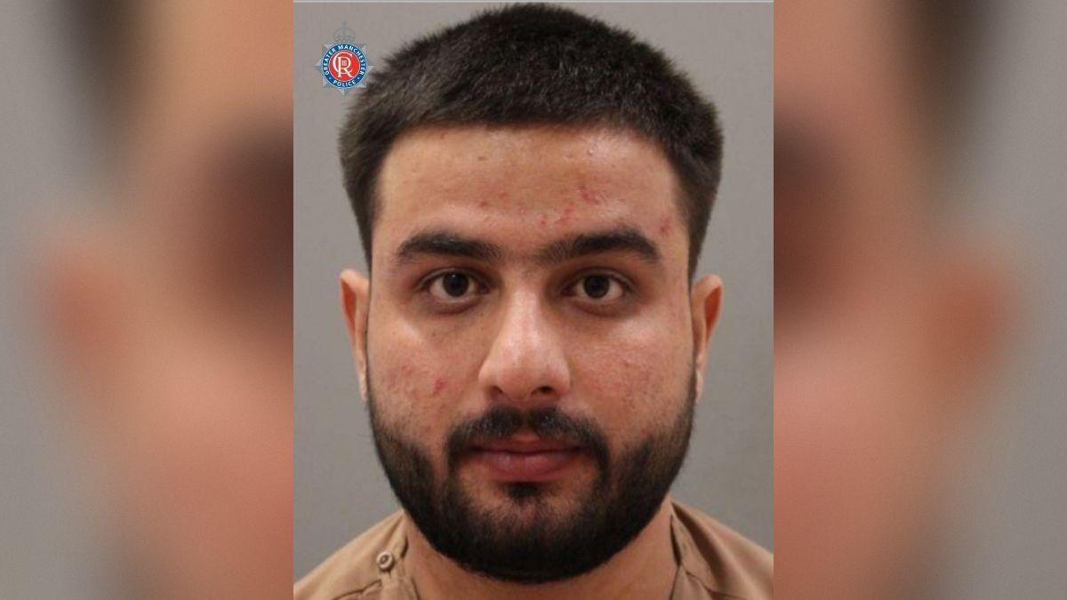 A mug shot of a man with short black hair and a beard.