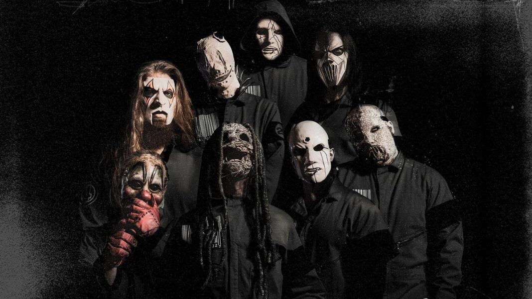 Eight members of Slipknot pose together in various masks. They all wear black outfits.