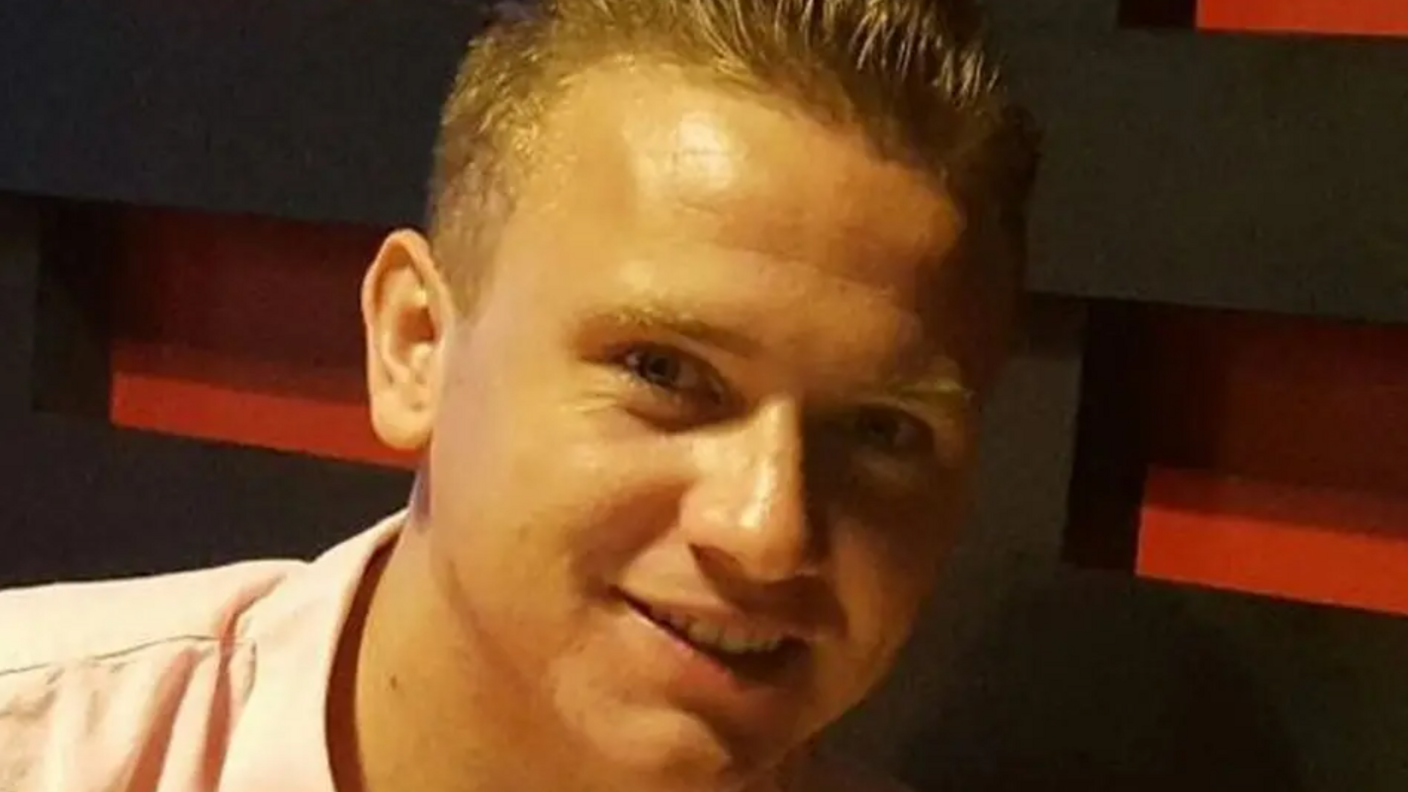 A headshot of a man who is wearing a shirt and smiling while looking into the camera.