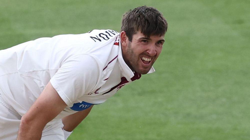 Craig Overton bowls a ball with his teeth showing