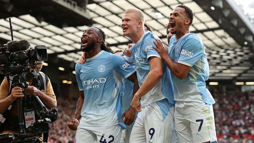 Erling Haaland and teammates celebrate a goal at Old Trafford stadium.
