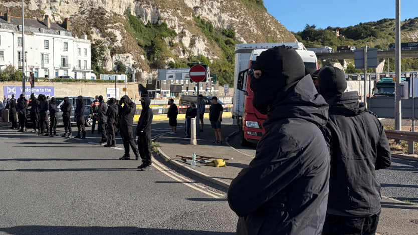 Black-clad and masked demonstrators blocking roads in Dover during a protest.