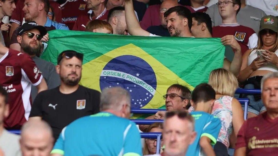 Large Brazil flag being held up by two Northampton Town fans in stand at Sixfields