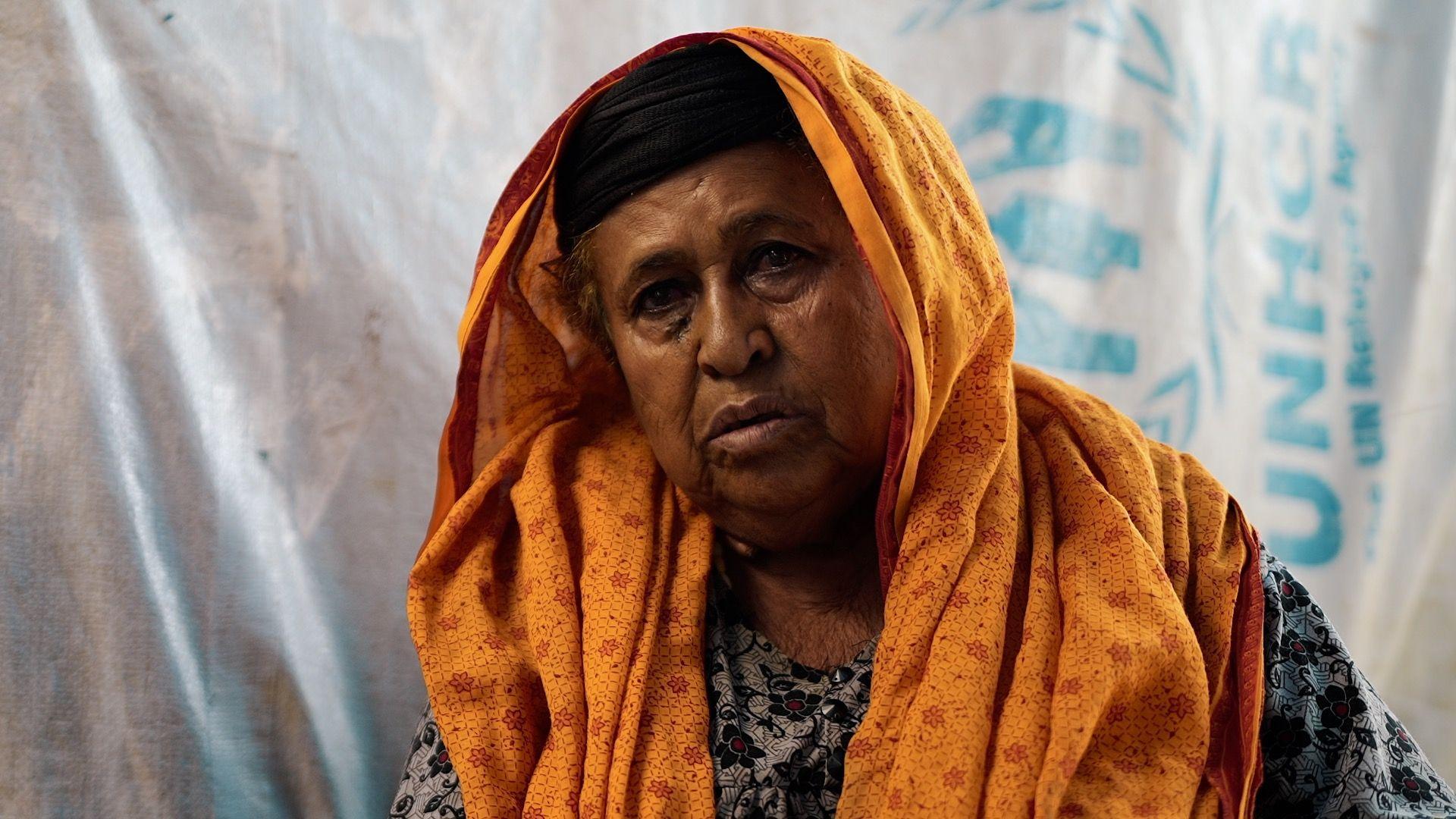 An elderly woman wearing a headscarf as she sits on the floor in the al-Monig displacement camp