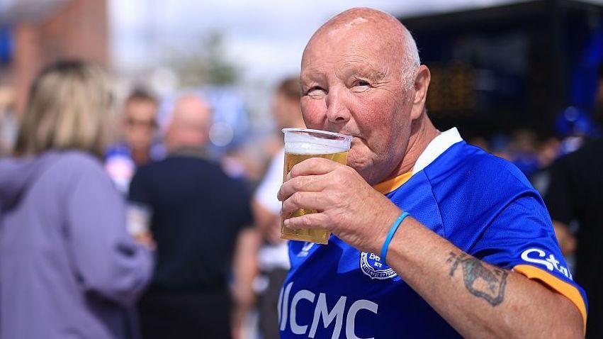 An Everton fan drinks a beer before the Premier League match against Crystal Palace