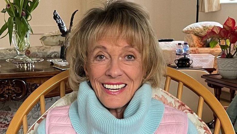 Esther Rantzen photographed towards the end of her life.  She is at home looking directly into camera and smiling.