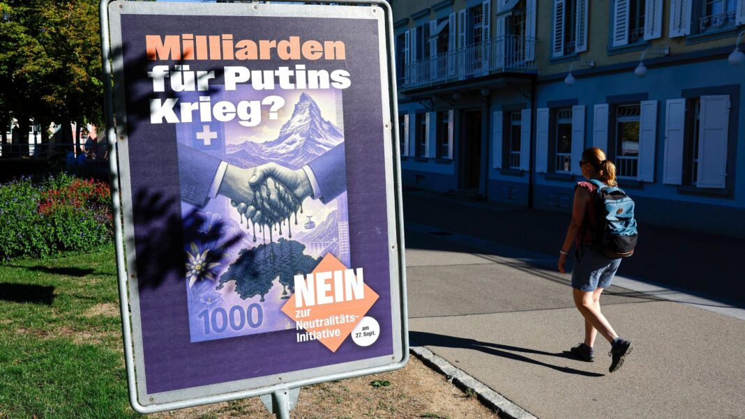 Switzerland rejects stricter interpretation of its neutrality A woman wearing a backpack walks past a placard against the vote on the "Neutrality Initiative" in Rheinfelden, Switzerland