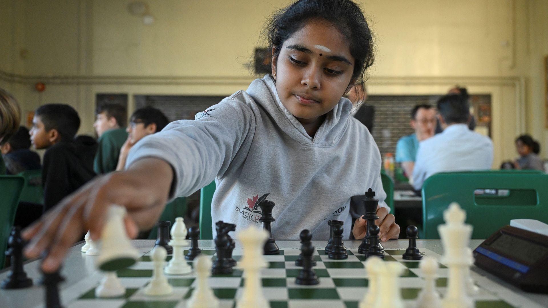 Bodhana Sivanandan pictured playing a chess piece on a chess board.