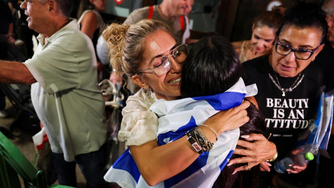 A woman smiles and embraces a person draped in an Israeli flag as passengers who were on the FlyDubai aircraft bound for Israel from the United Arab Emirates are greeted by their friends and family, as they arrive at the Ben Gurion International Airport.