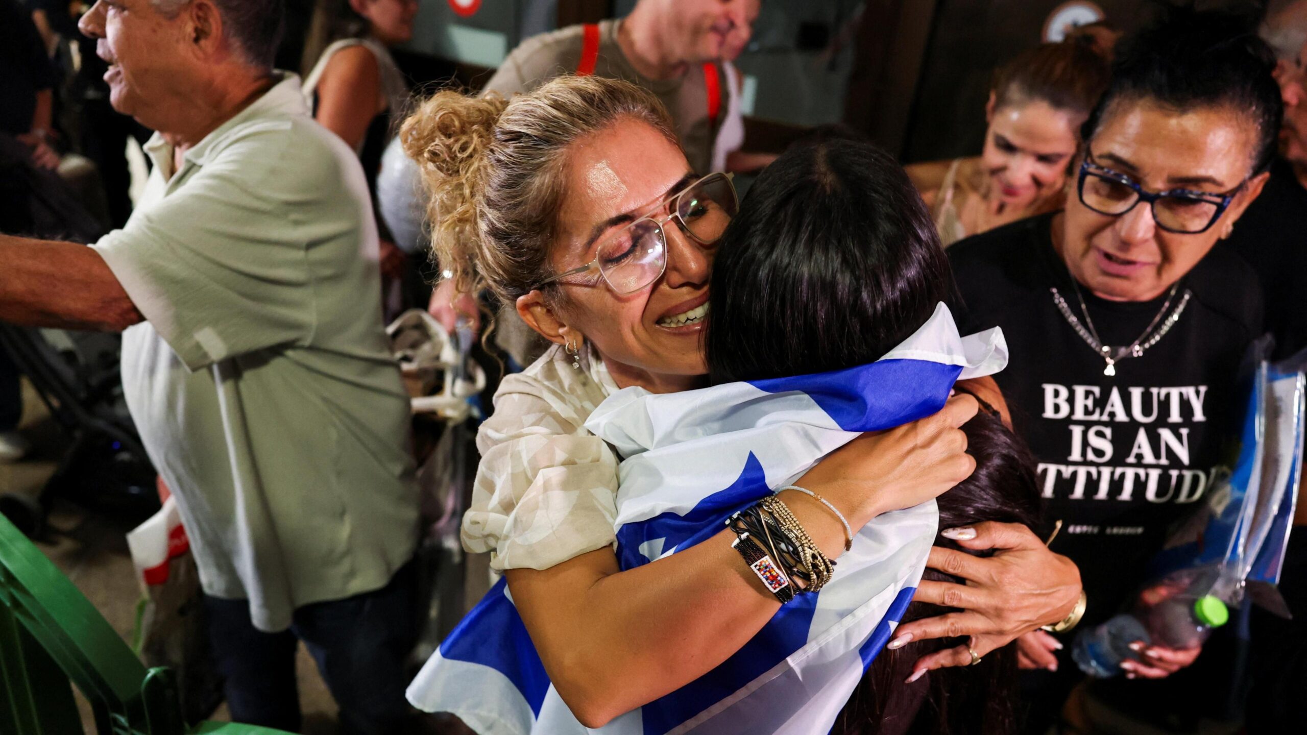 A woman smiles and embraces a person draped in an Israeli flag as passengers who were on the FlyDubai aircraft bound for Israel from the United Arab Emirates are greeted by their friends and family, as they arrive at the Ben Gurion International Airport.