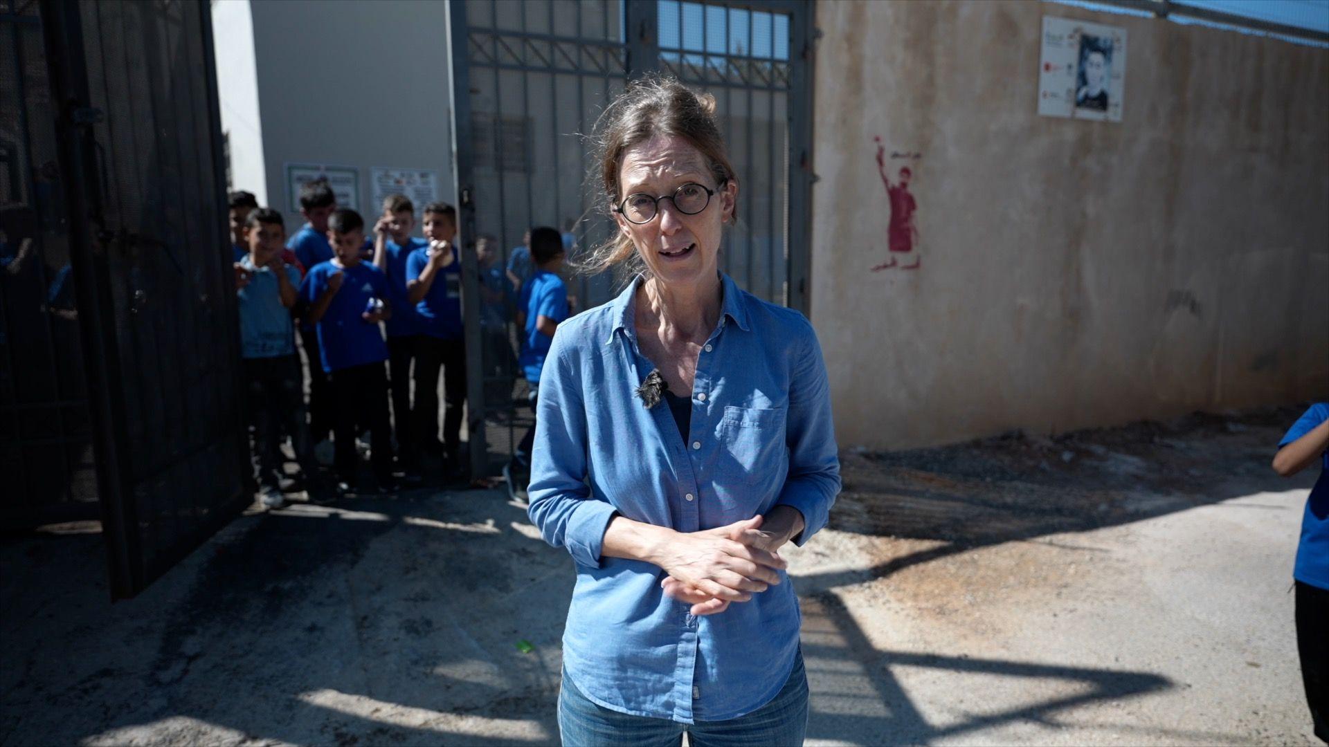 Lucy Williamson in front of children in school uniform.