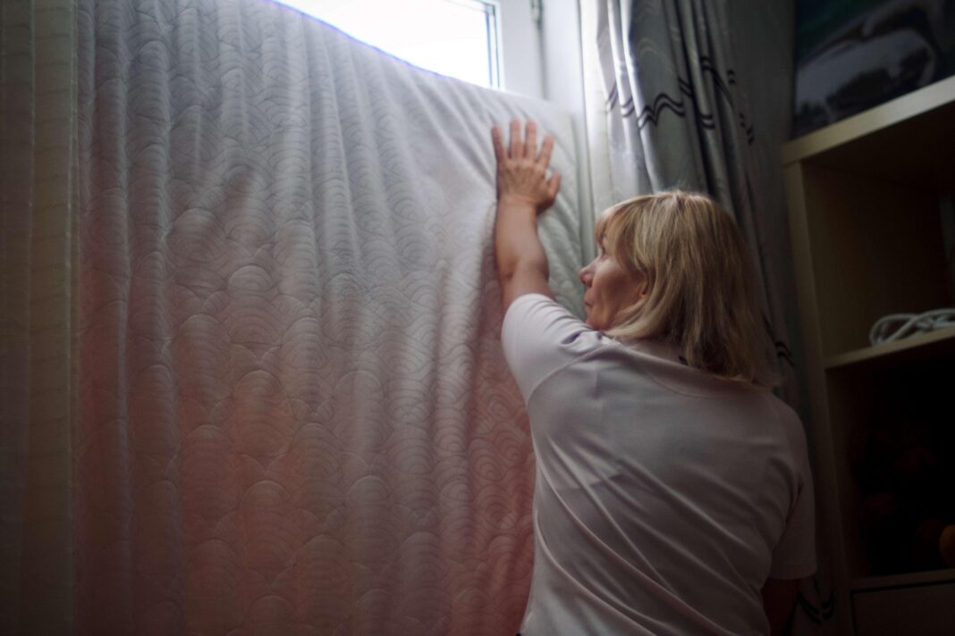 A four-minute warning isn’t enough: Russia’s new relentless missile tactics exhaust Kyiv residents Olha is seen fitting a mattress in the window. She's wearing a white t-shirt and has blonde hair